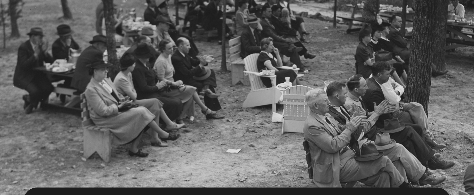 Black and white image shows an audience clapping in one of the Civilian Conservation Corps' outdoor summer vacation spots.